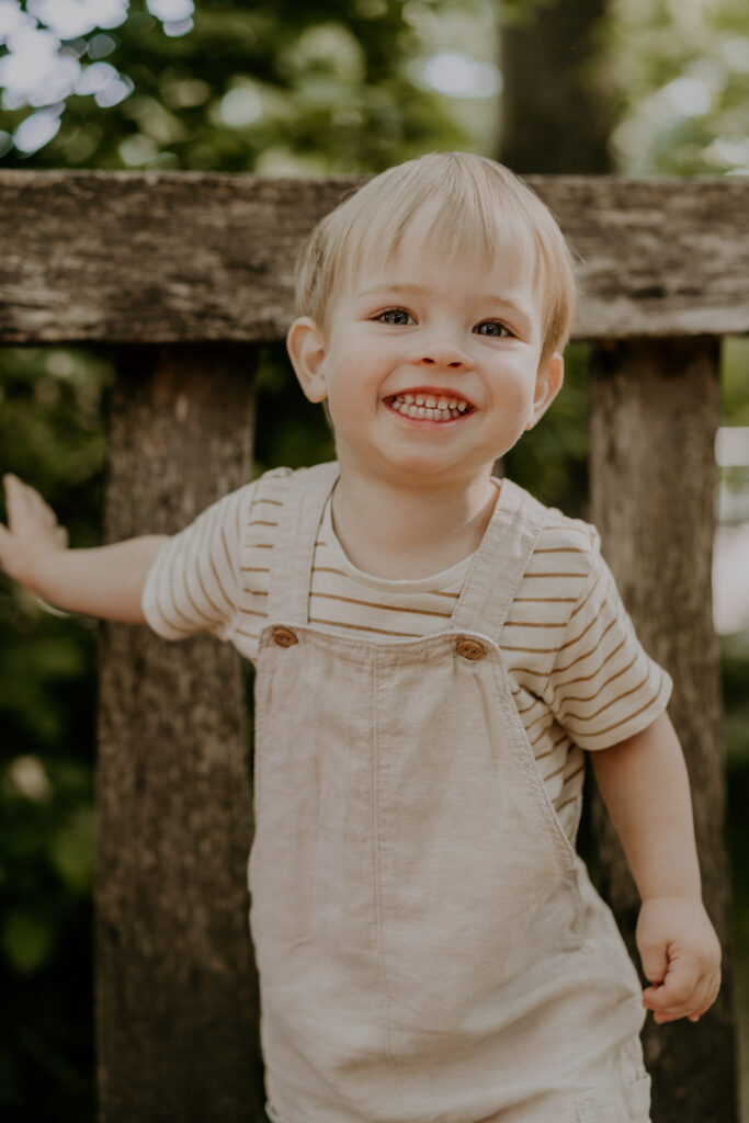 Blonder Junge lacht ausgelassen im Gartenbereich der Kita