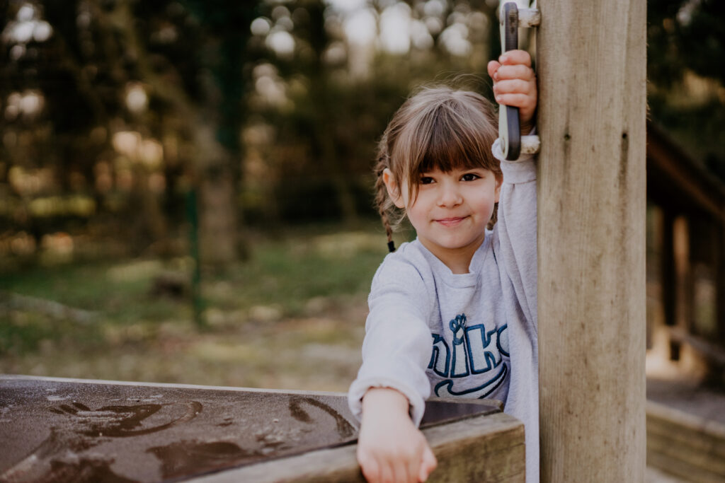 Mädchen spielt fröhlich an einem Holzspielplatz