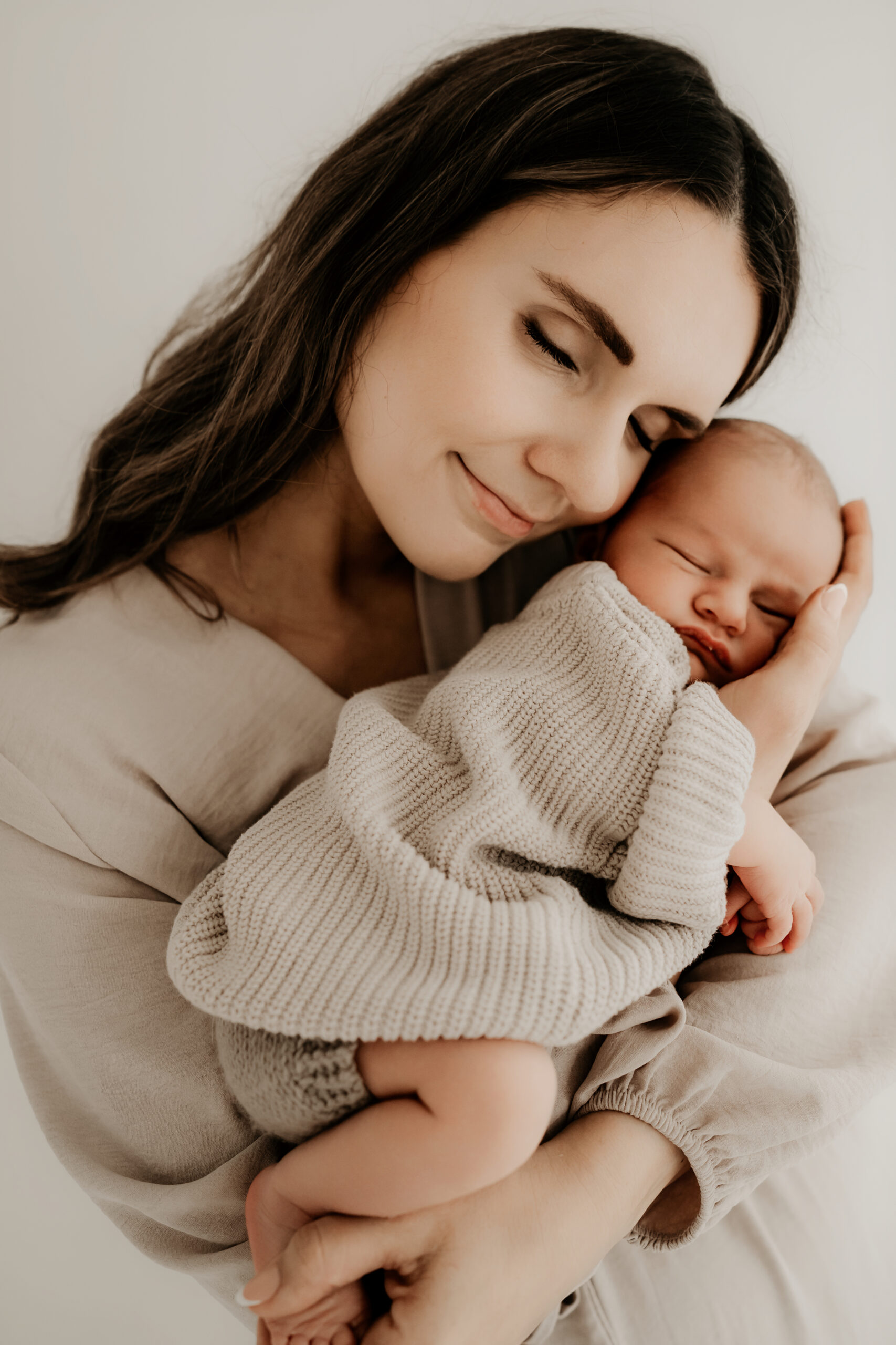 Neugeborenes schläft an der Brust der Mutter während eines emotionalen Babyshootings