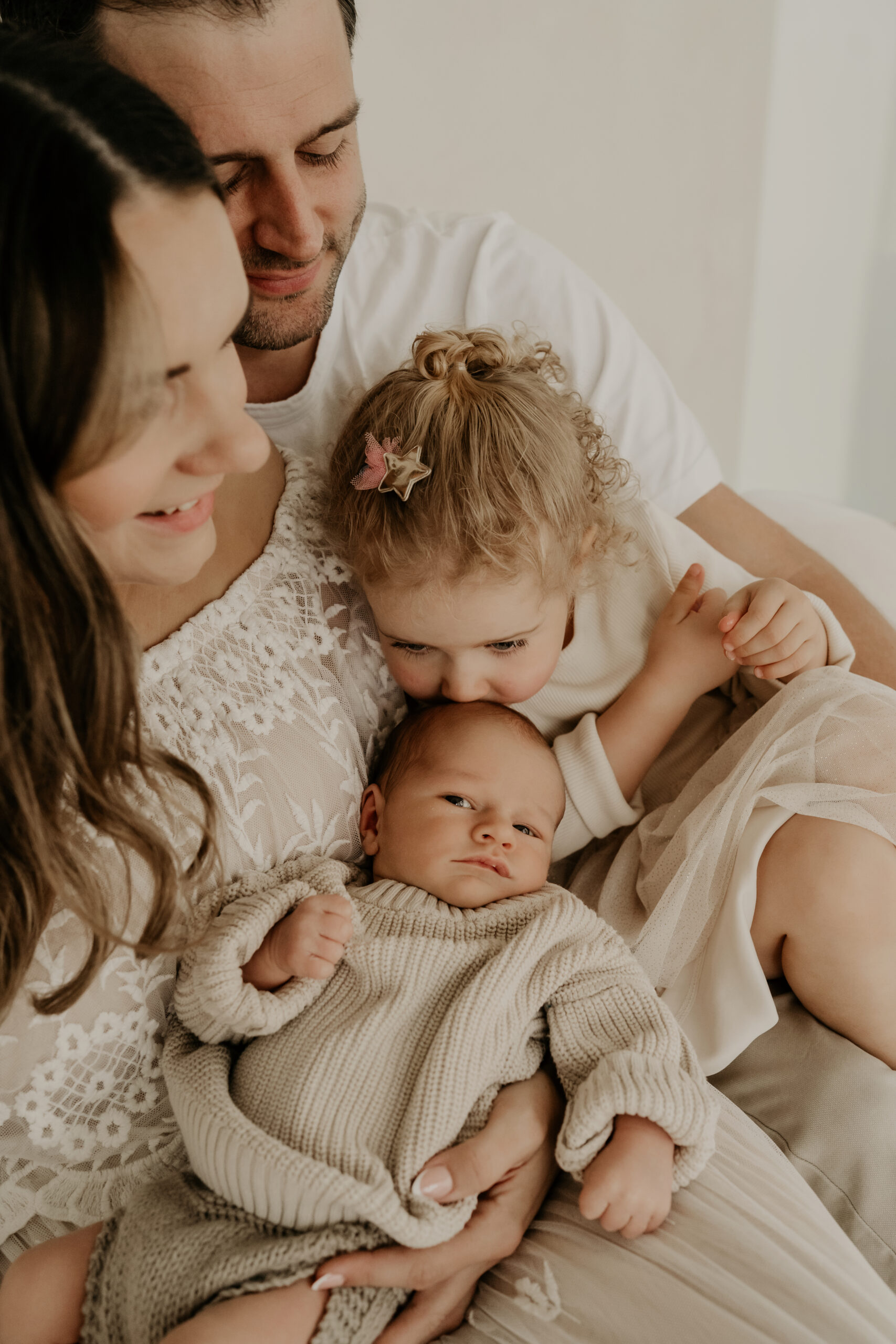 Eltern schauen lächelnd auf ihr Baby beim Shooting