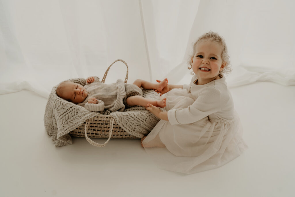 Große Schwester kuschelt mit ihrem Bruder beim Newbornshooting