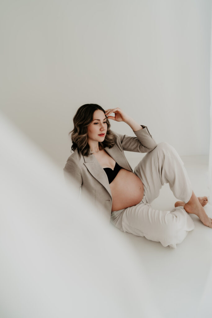 Schwangere Frau entspannt im hellen Studio liegend fotografiert