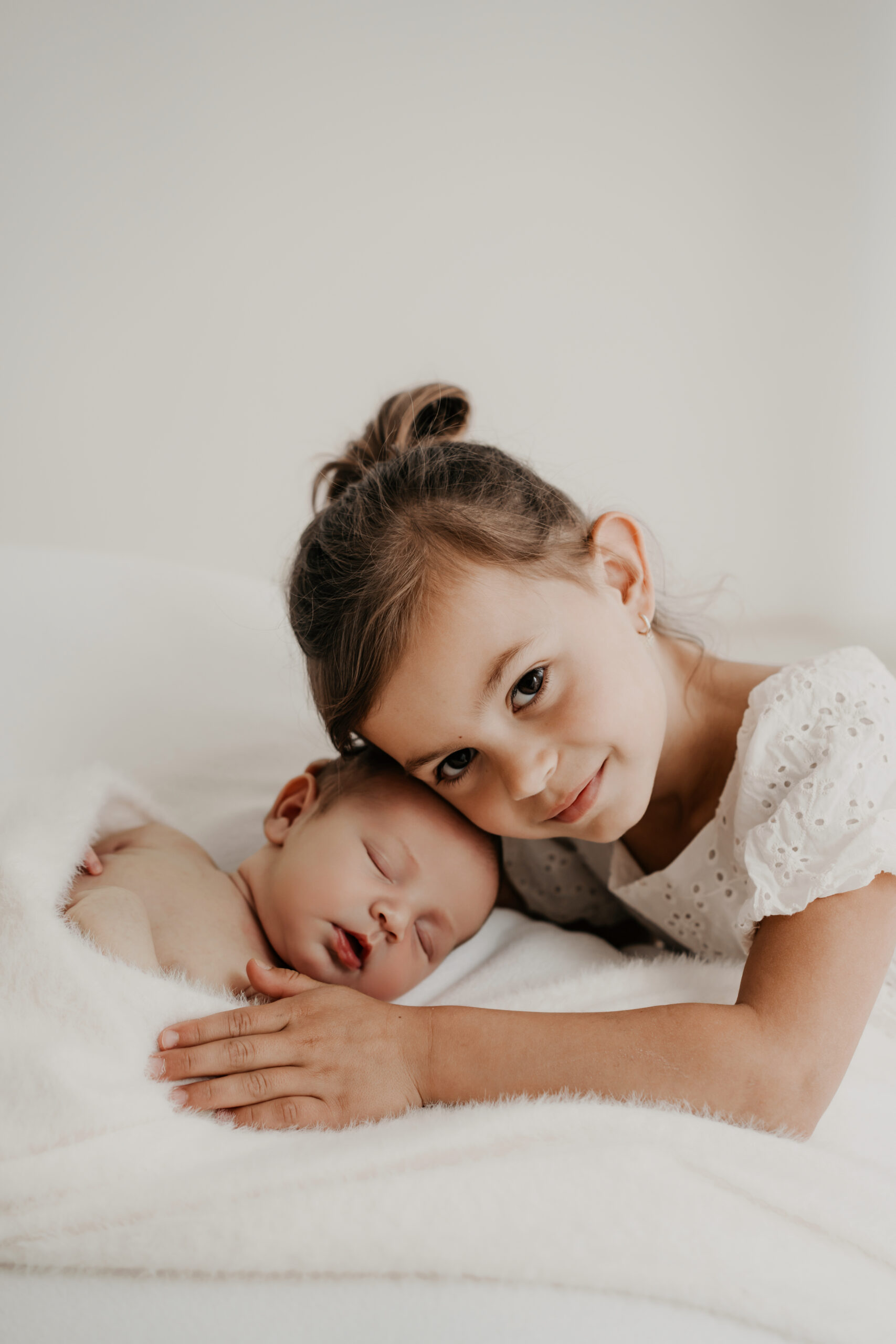 newbornshooting.jpg Große Schwester hält ihren kleinen Bruder liebevoll im Arm während eines entspannten Newbornshootings.