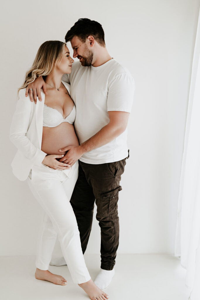 Natürliches Paarfoto voller Zuneigung während eines Babybauchshootings.
