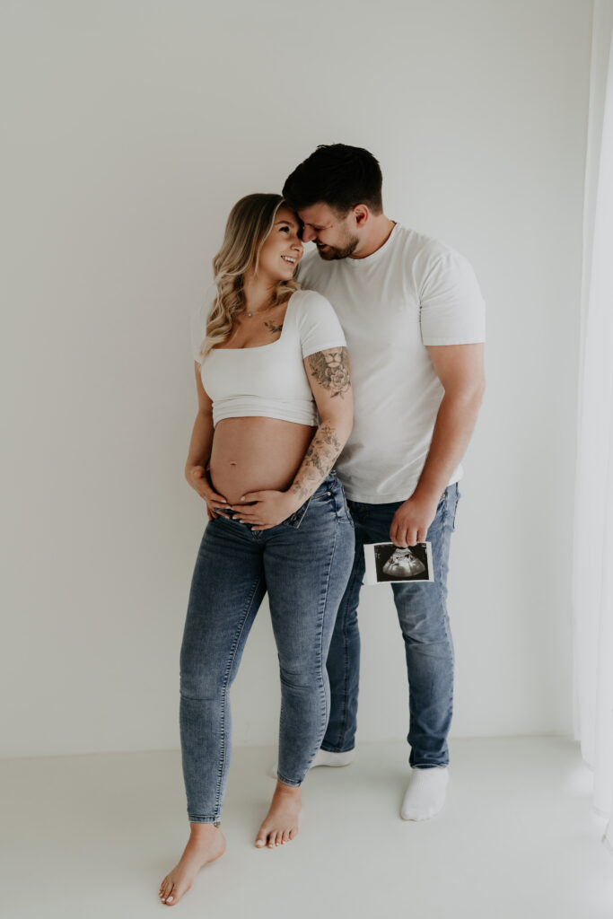Werdende Eltern mit Ultraschallbild während ihres Babybauchshootings im Studio.