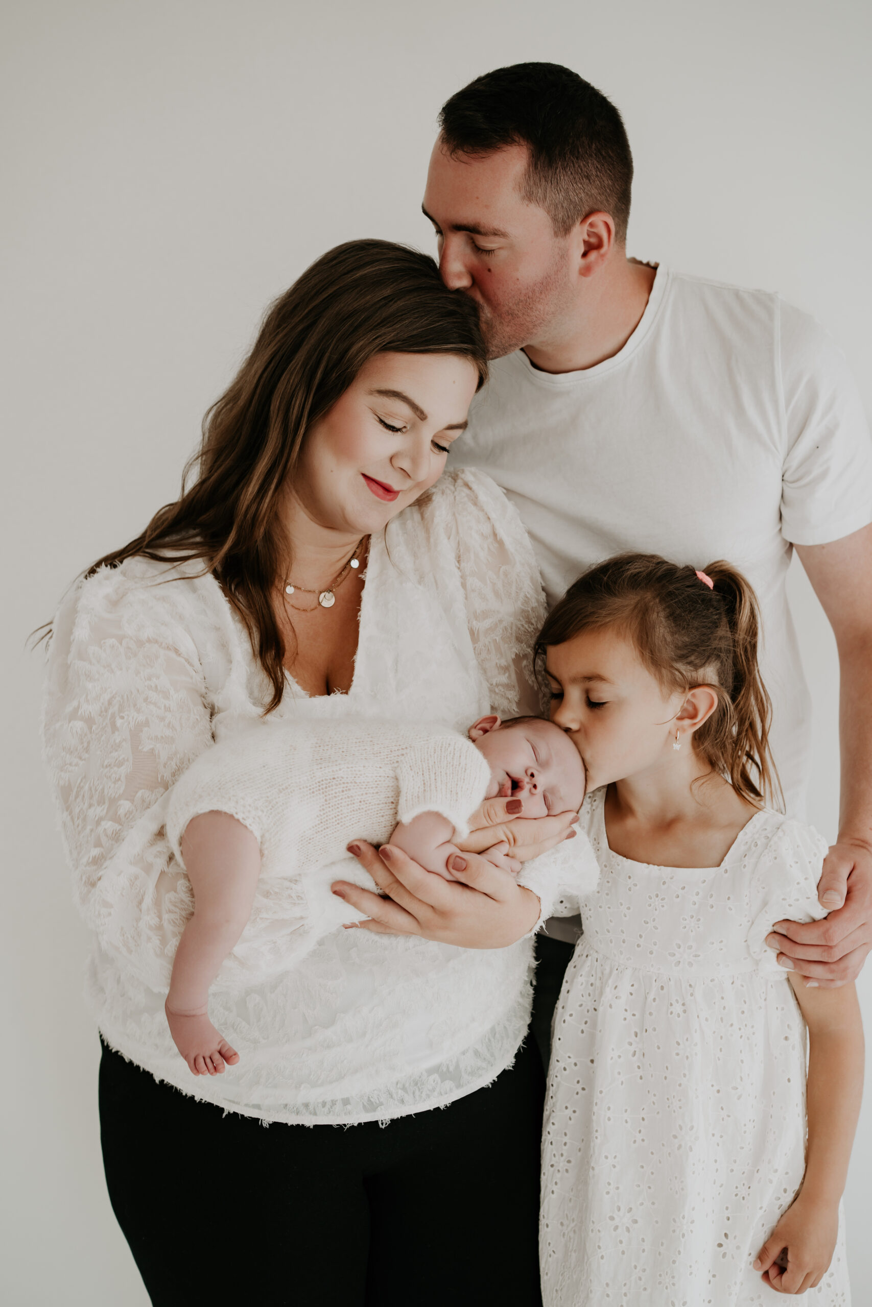 Eltern und große Schwester begrüßen ihr Neugeborenes bei einem natürlichen Newbornshooting im Studio in Lengerich.