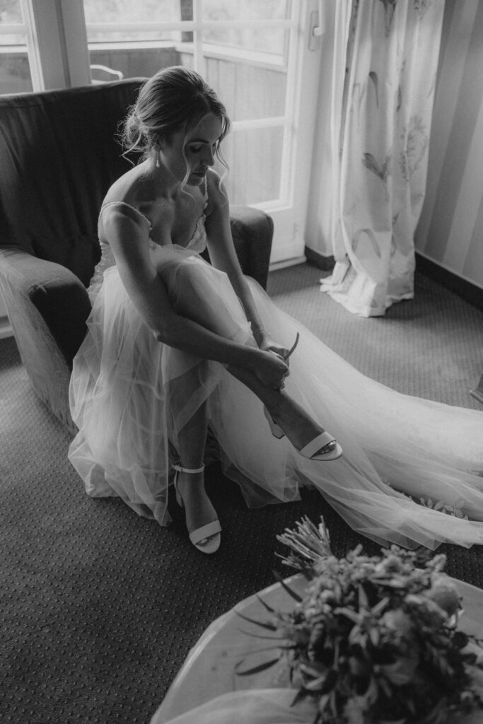 Braut beim Anziehen ihrer Schuhe während des Getting Readys